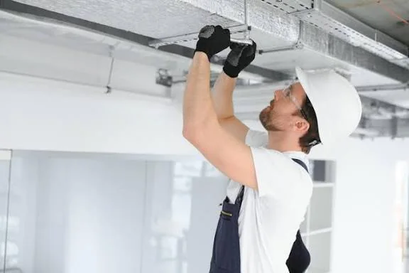 Technician model inspecting overhead HVAC ductwork and airflow equipment
