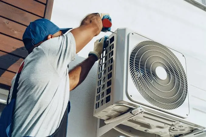 Technician model checking a wall-mounted residential heat pump condenser