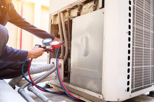 Technician model checking refrigerant pressure on residential cooling equipment